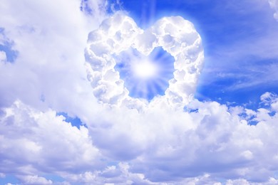 Image of Bright light shining through heart made of clouds in sky. Love of God, concept