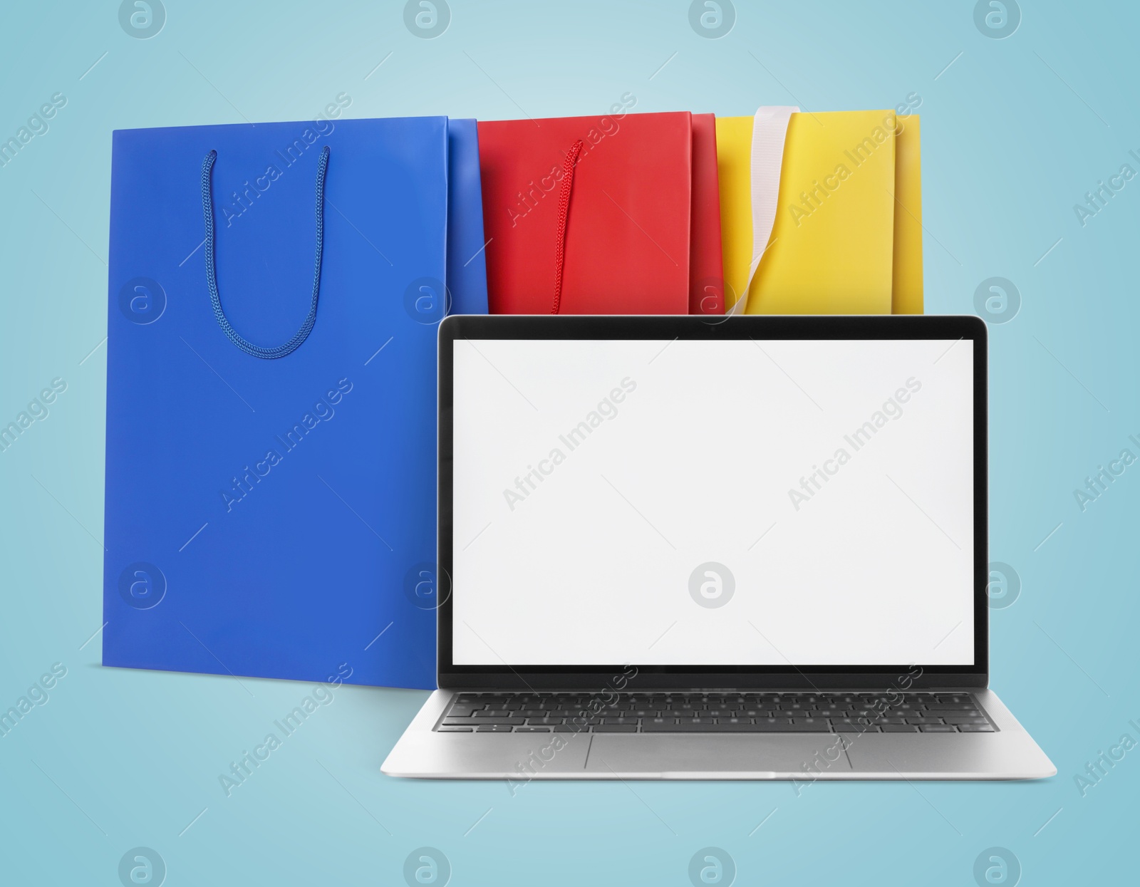 Image of Laptop and shopping bags on light blue background. Concept of online shopping, purchase via internet