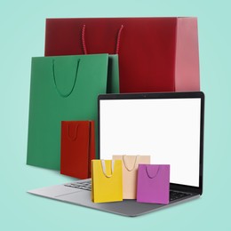 Image of Laptop and shopping bags on turquoise background. Concept of online shopping, purchase via internet