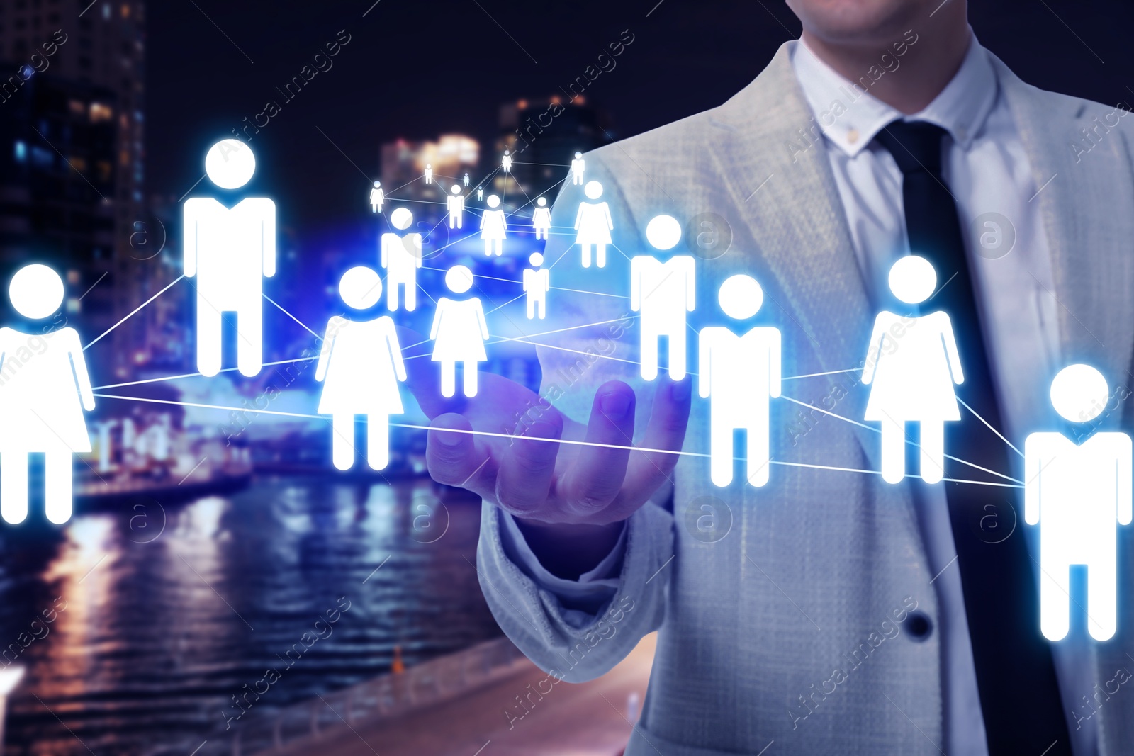 Image of Human resource. Businessman holding virtual scheme with people figures against night cityscape, closeup