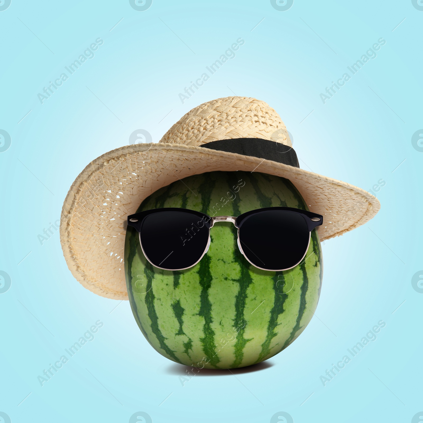 Image of Watermelon with straw hat and sunglasses on light blue background