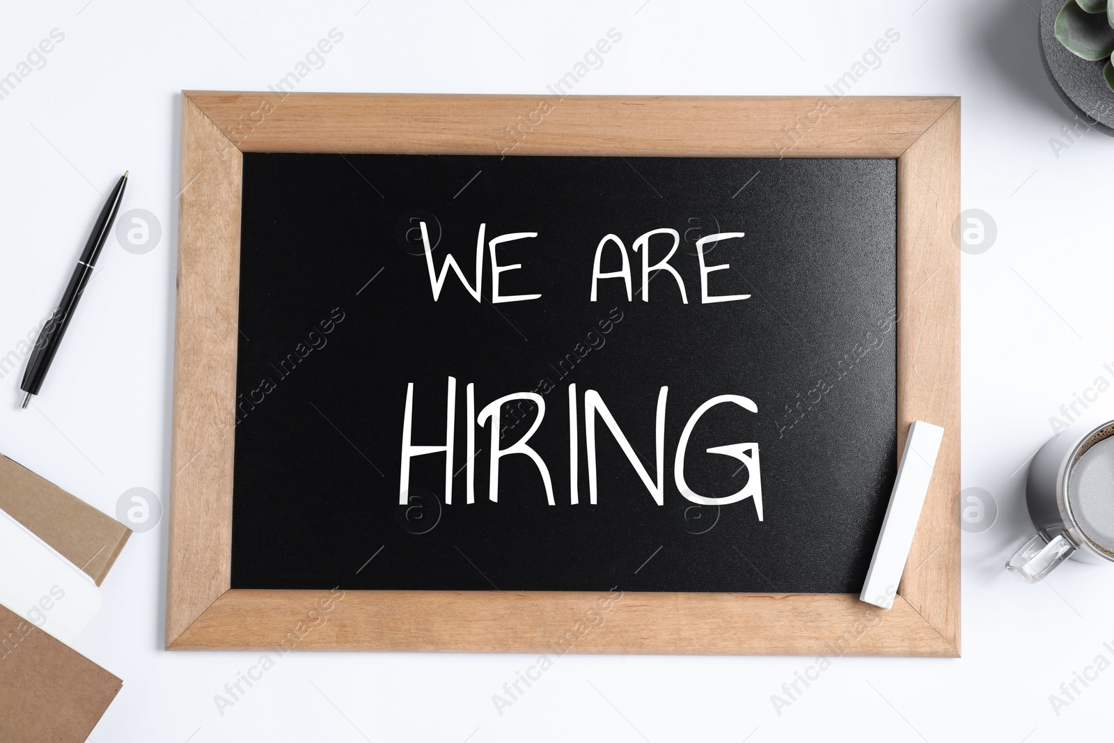 Image of Small chalkboard with text We Are Hiring on white table, top view. Human resource