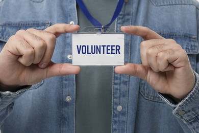 Image of Man holding badge with word Volunteer, closeup