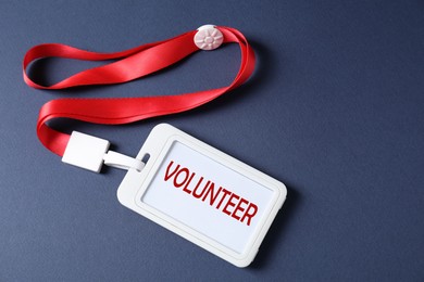 Image of Badge with word Volunteer on dark blue background, top view