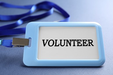 Image of Badge with word Volunteer on blue background, closeup