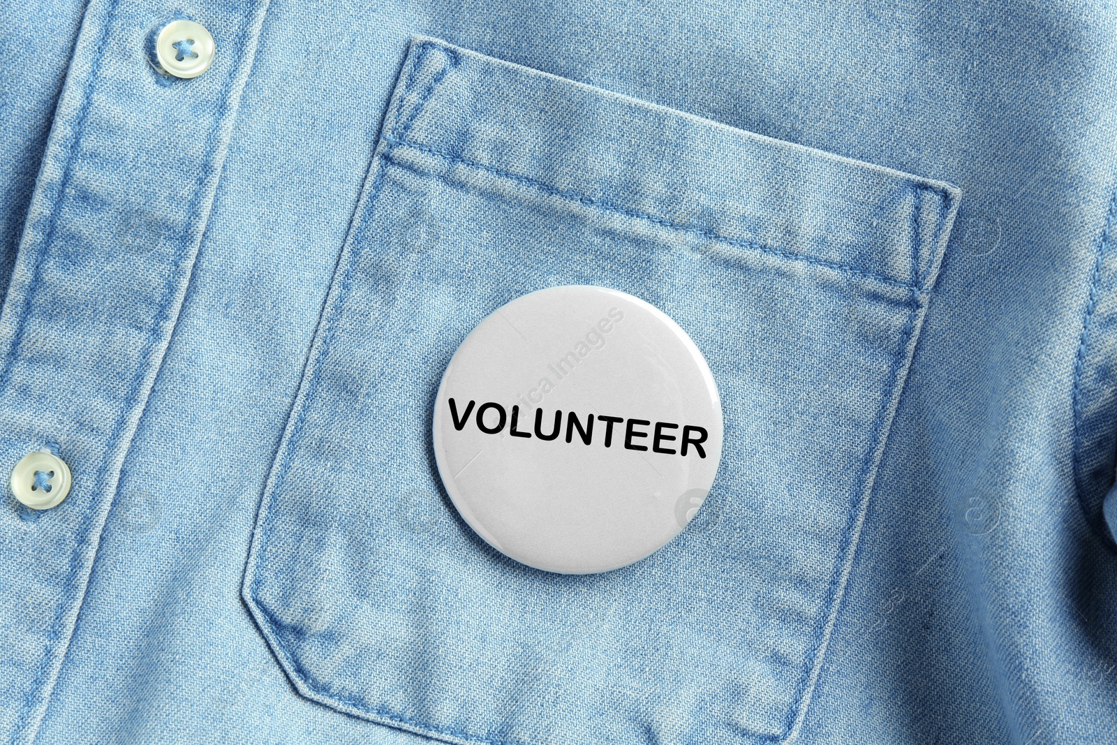 Image of Button badge with word Volunteer attached to denim shirt, closeup