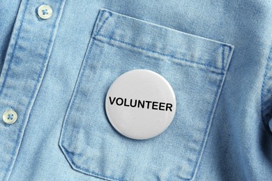 Image of Button badge with word Volunteer attached to denim shirt, closeup