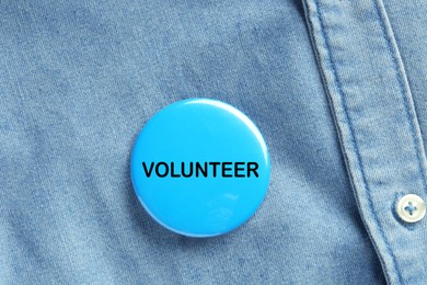 Image of Button badge with word Volunteer attached to denim shirt, closeup