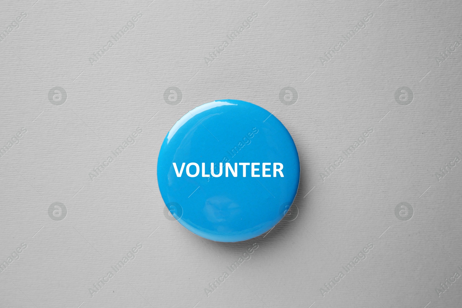 Image of Button badge with word Volunteer on grey background, top view