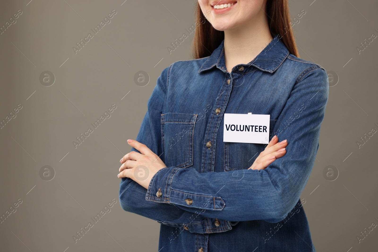 Image of Volunteer with badge on grey background, closeup. Space for text