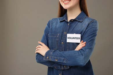 Image of Volunteer with badge on grey background, closeup. Space for text