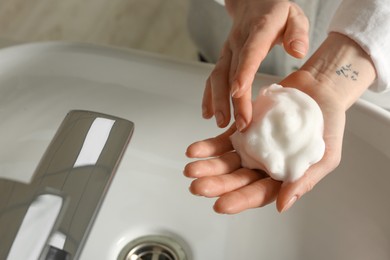 Photo of Woman washing hands with cleansing foam near sink in bathroom, closeup. Space for text