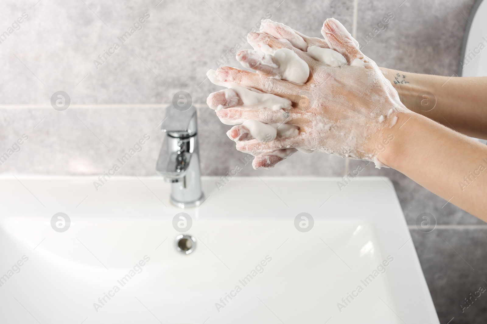 Photo of Woman washing hands with cleansing foam near sink in bathroom, closeup. Space for text