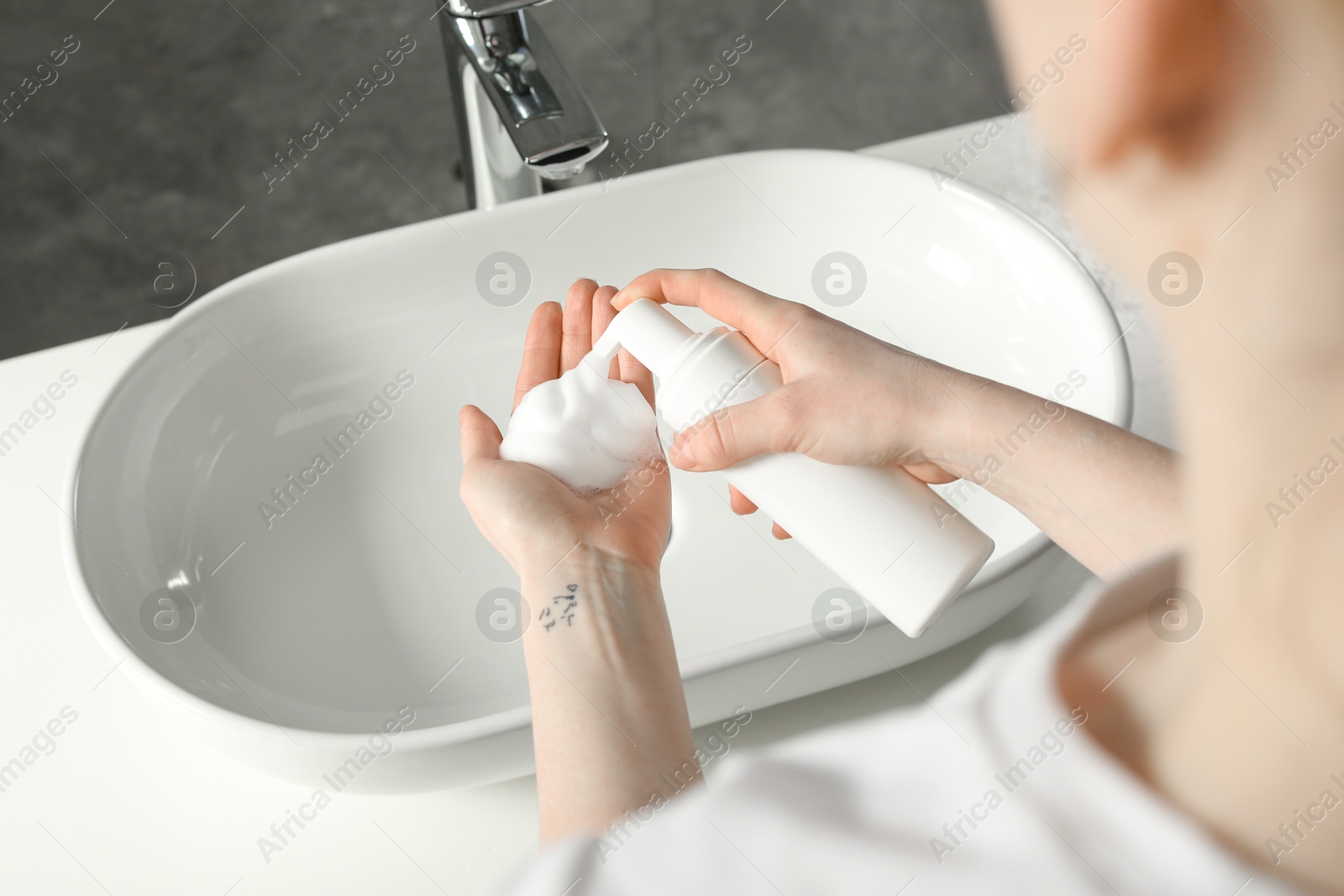 Photo of Woman washing hands with cleansing foam near sink in bathroom, closeup