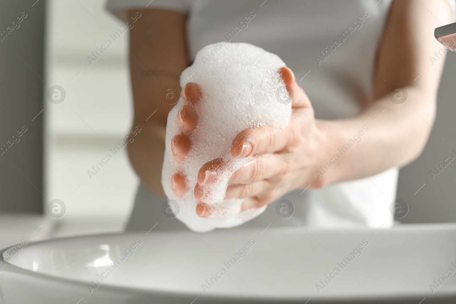 Photo of Woman washing hands with cleansing foam near sink in bathroom, closeup