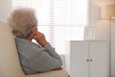 Photo of Loneliness concept. Sad senior woman sitting in armchair at home