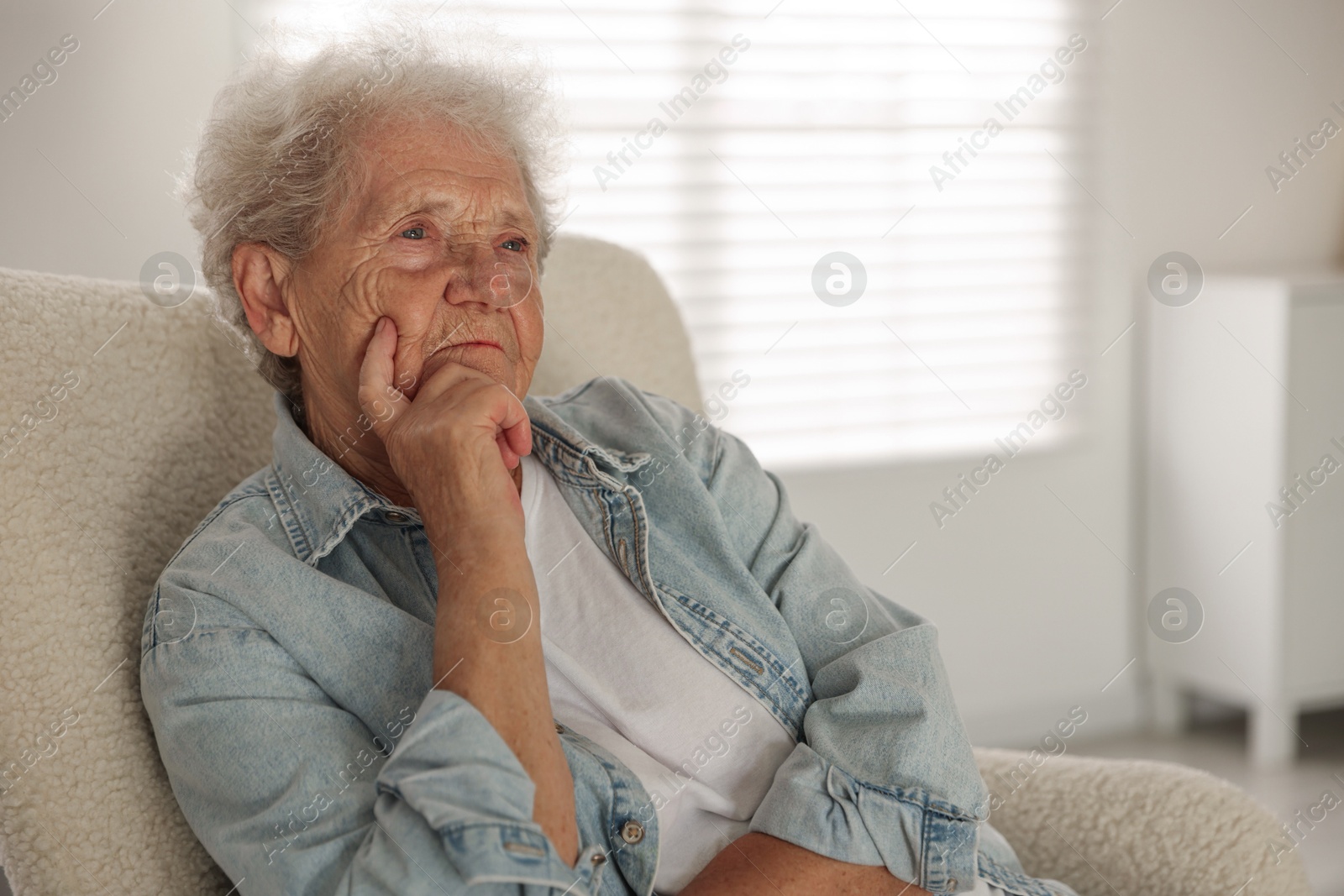 Photo of Loneliness concept. Sad senior woman sitting in armchair at home