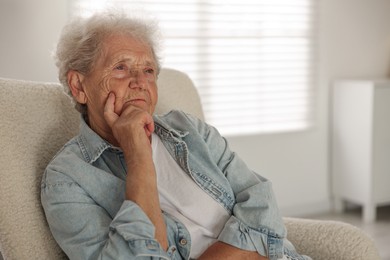 Photo of Loneliness concept. Sad senior woman sitting in armchair at home