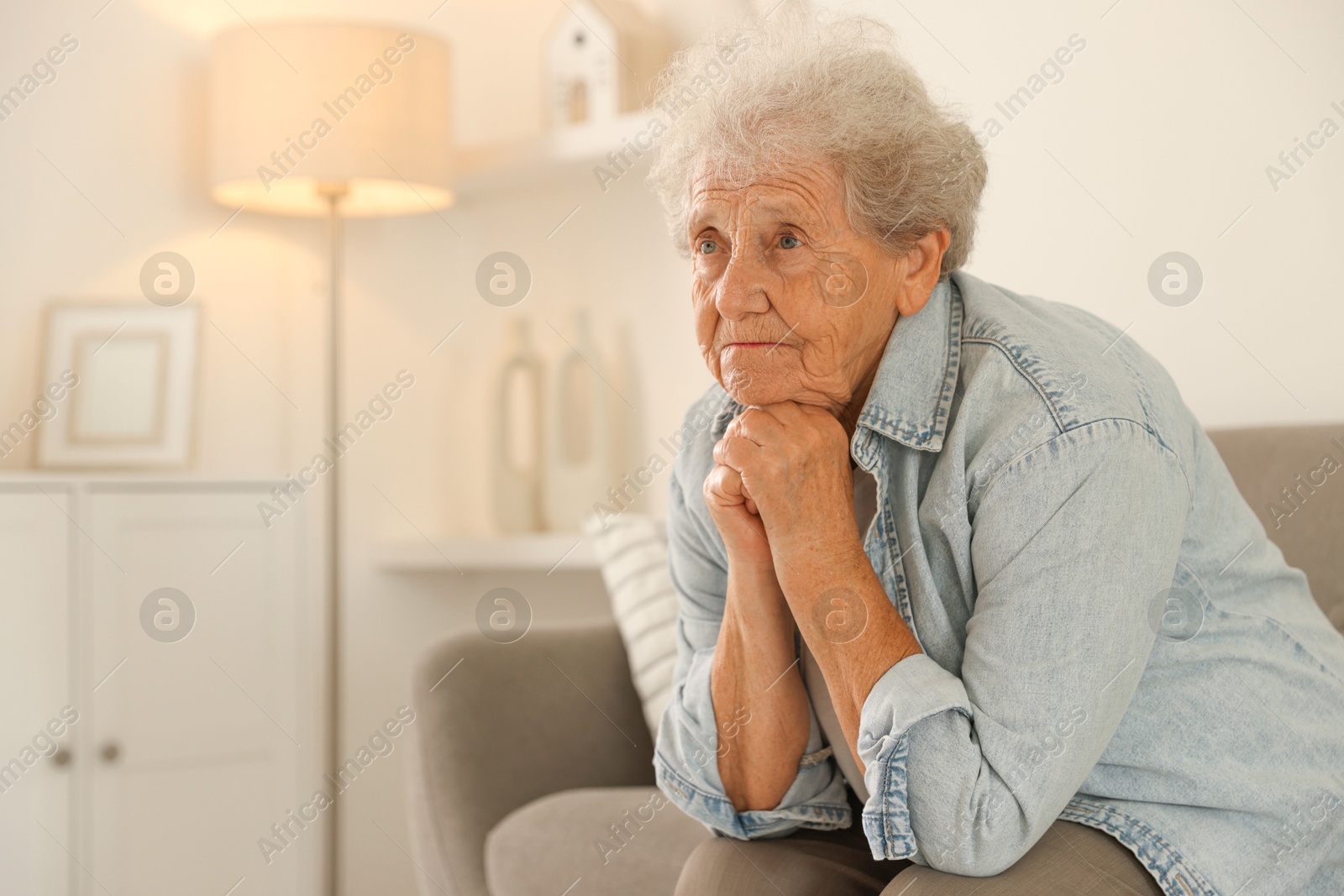 Photo of Loneliness concept. Sad senior woman sitting on sofa at home