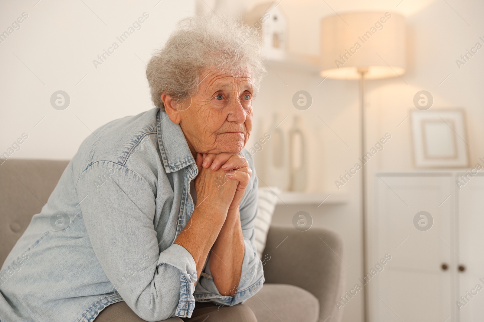 Photo of Loneliness concept. Sad senior woman sitting on sofa at home