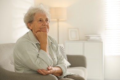 Photo of Loneliness concept. Sad senior woman sitting on sofa at home