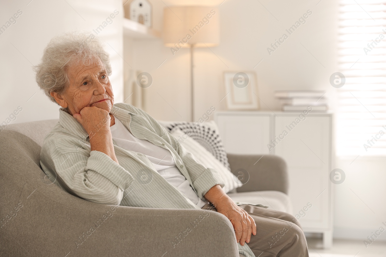 Photo of Loneliness concept. Sad senior woman sitting on sofa at home