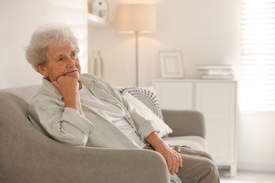 Photo of Loneliness concept. Sad senior woman sitting on sofa at home