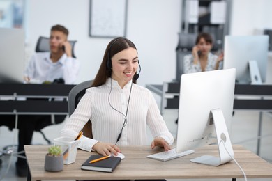 Photo of Saleswoman talking to client via headset at desk in office