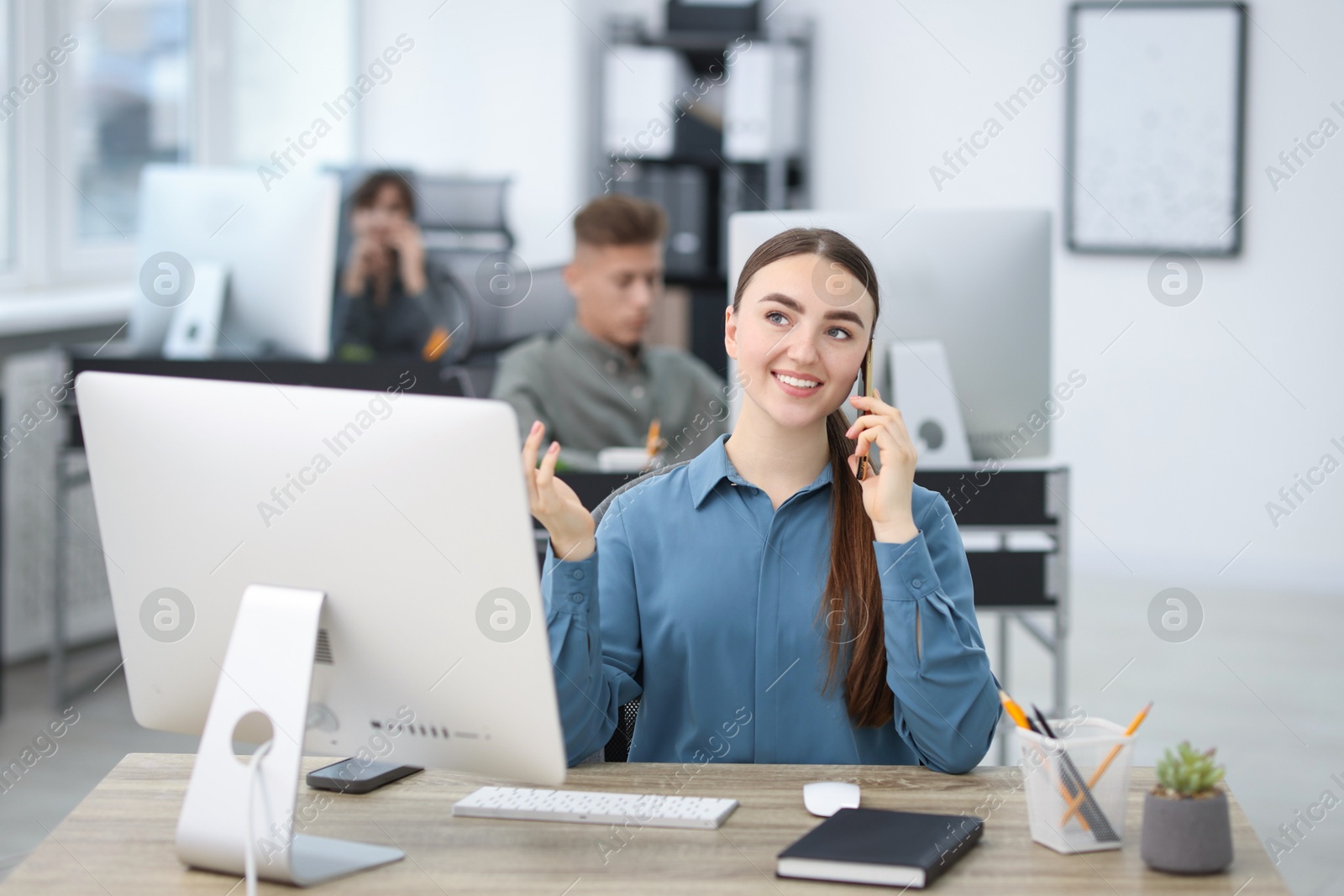 Photo of Saleswoman talking on phone at desk in office