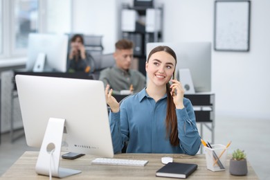 Photo of Saleswoman talking on phone at desk in office