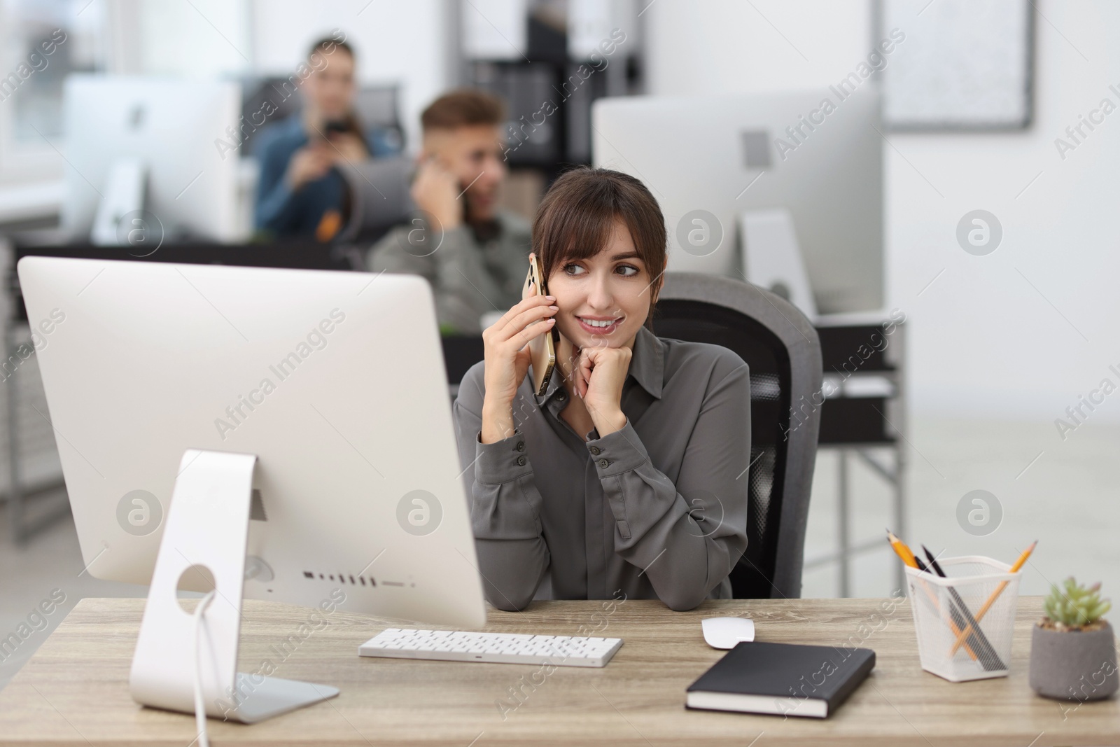 Photo of Saleswoman talking on phone at desk in office