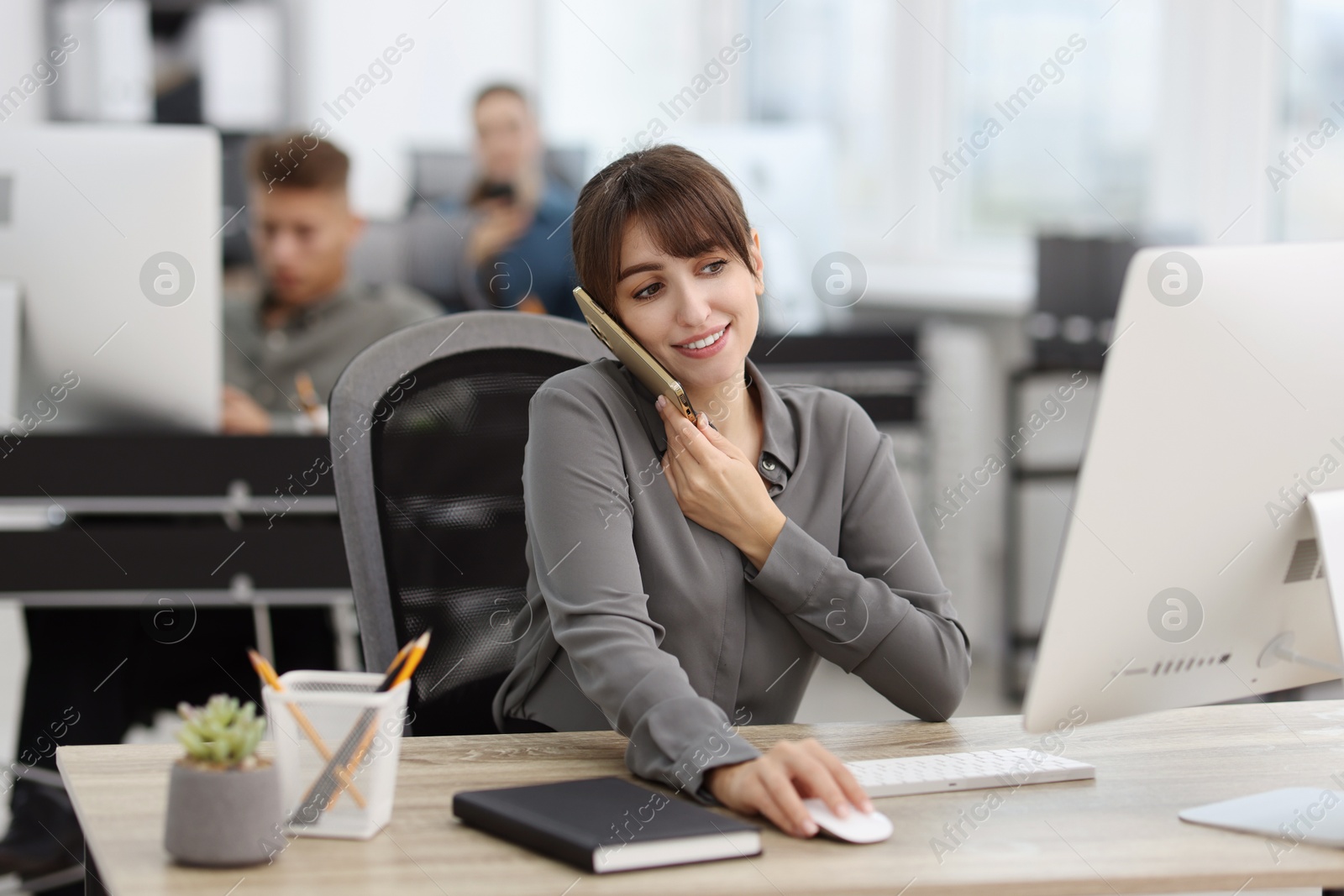 Photo of Saleswoman talking on phone at desk in office