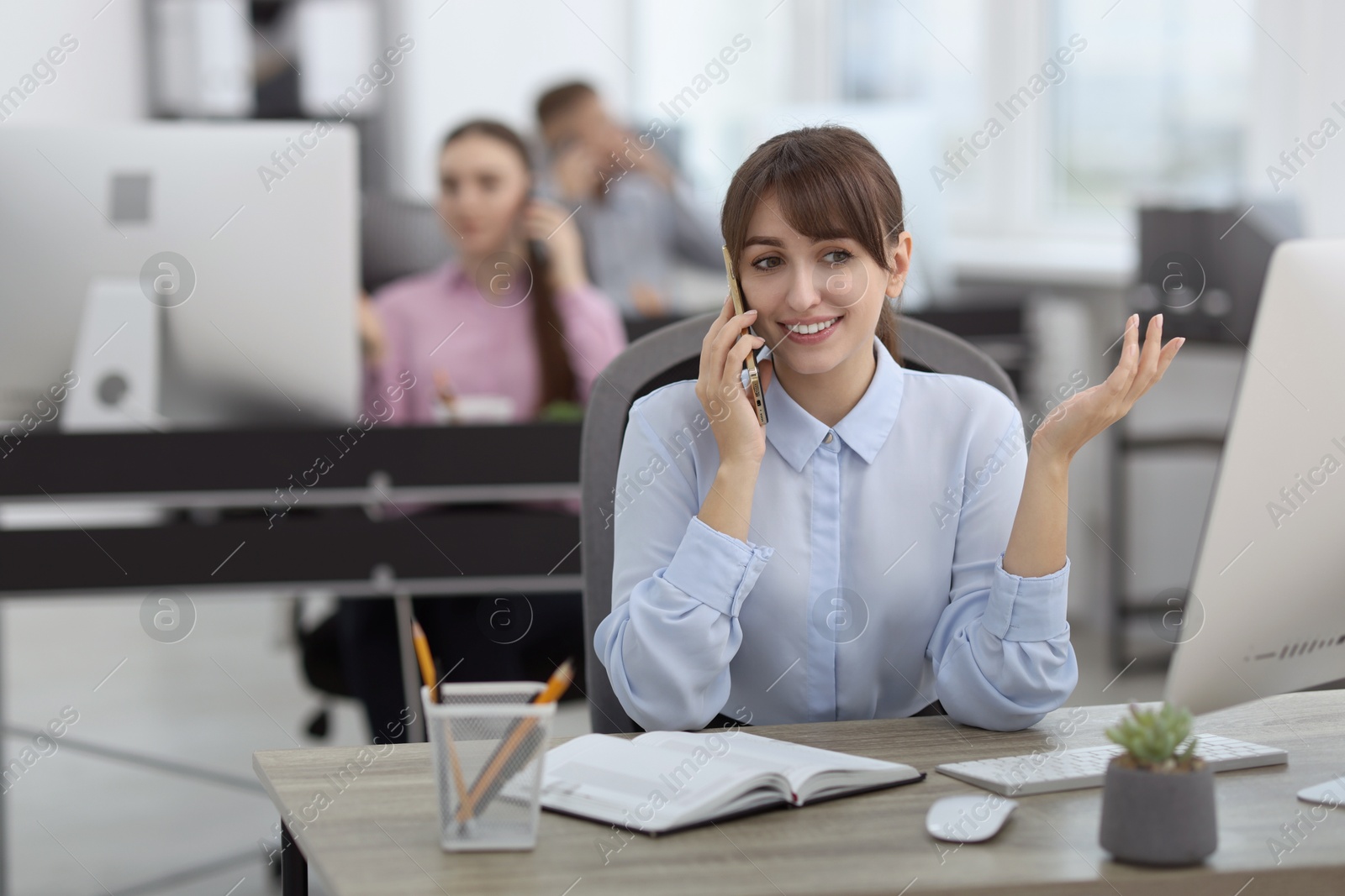 Photo of Saleswoman talking on phone at desk in office