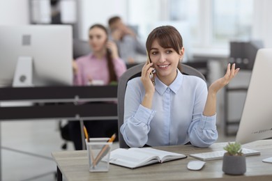 Photo of Saleswoman talking on phone at desk in office