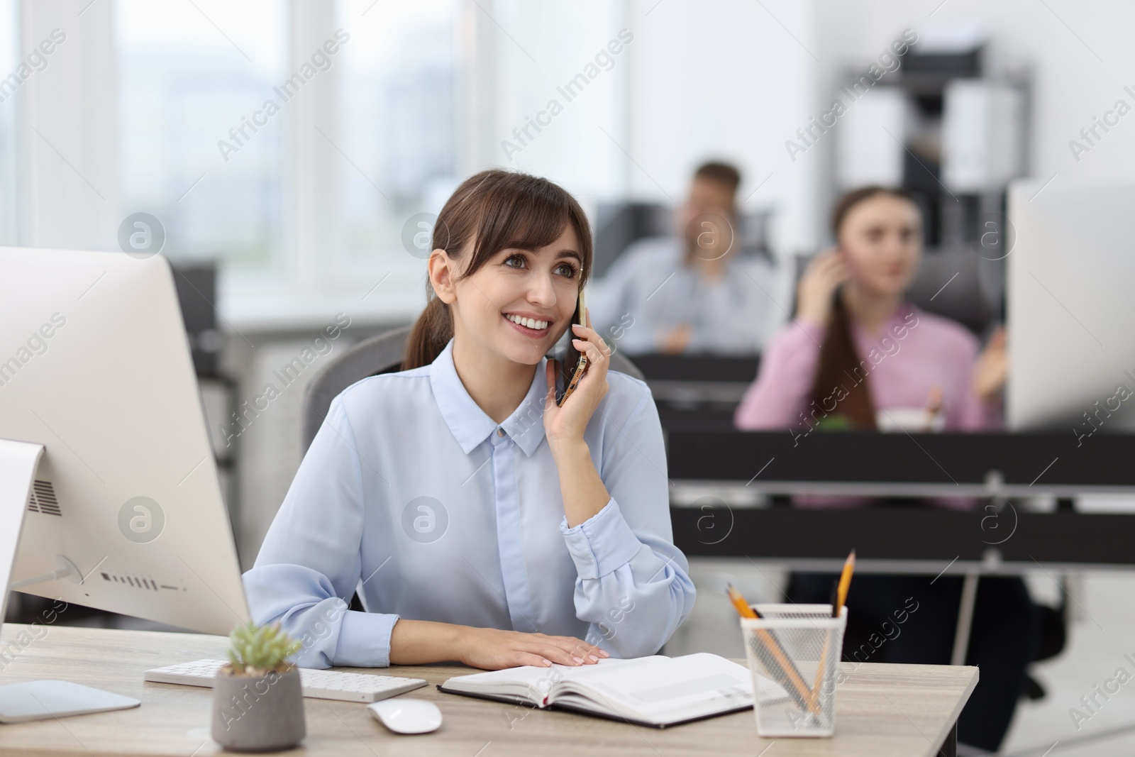 Photo of Saleswoman talking on phone at desk in office