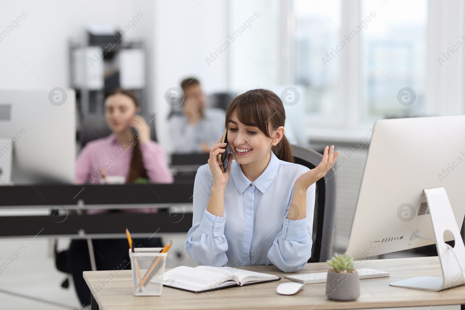 Photo of Saleswoman talking on phone at desk in office