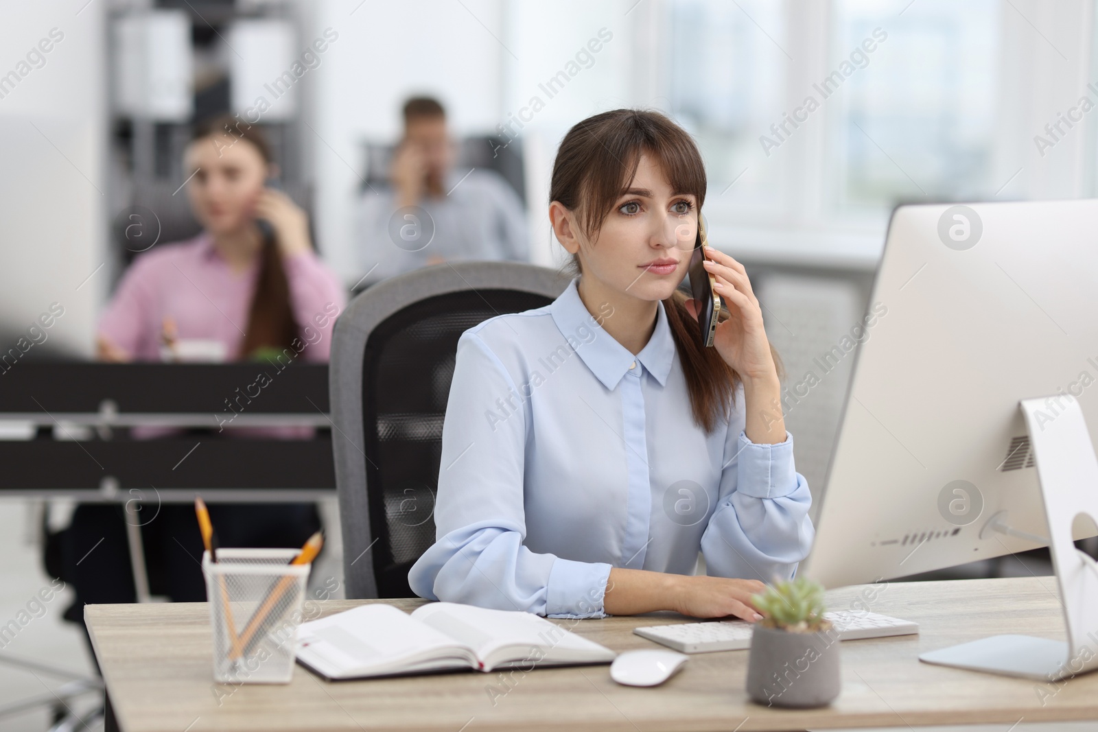 Photo of Saleswoman talking on phone at desk in office