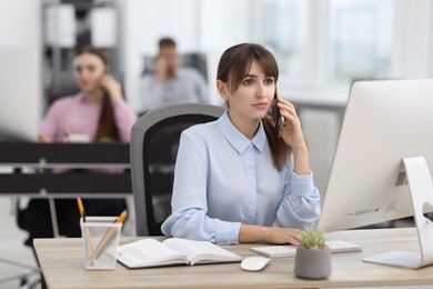 Photo of Saleswoman talking on phone at desk in office