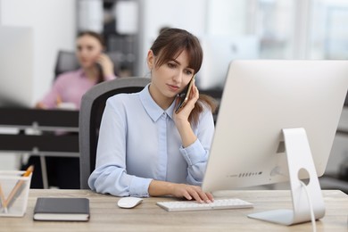 Photo of Saleswoman talking on phone at desk in office