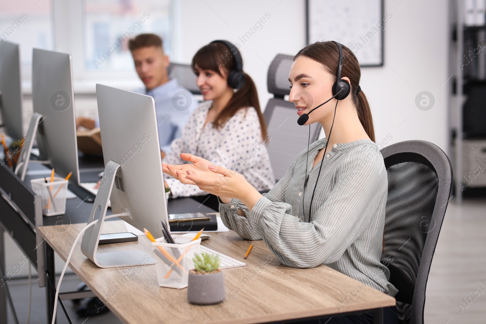 Photo of Saleswoman talking to client via headset at desk in office