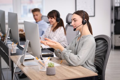 Photo of Saleswoman talking to client via headset at desk in office