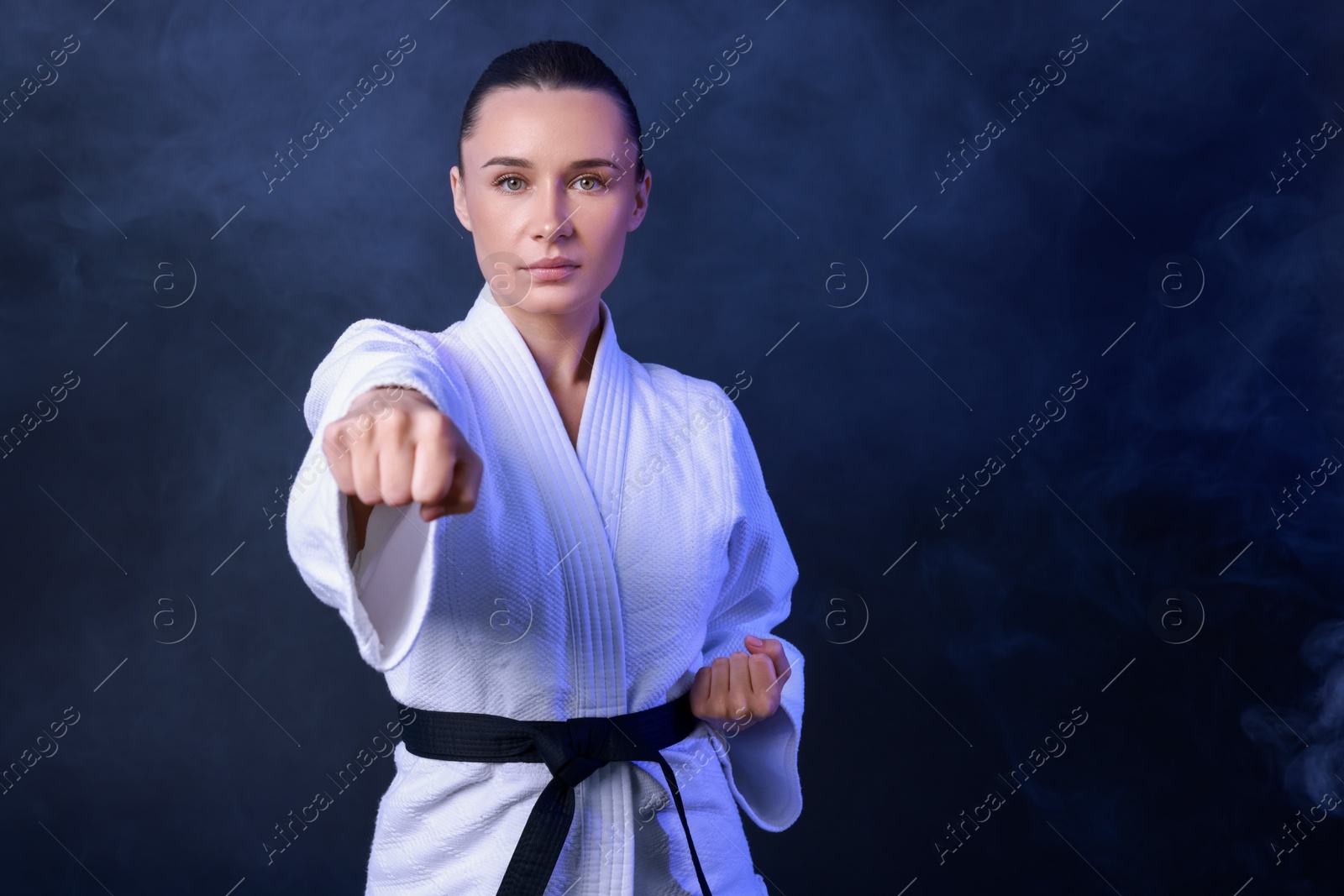 Photo of Karate fighter in kimono and smoke on dark background, space for text