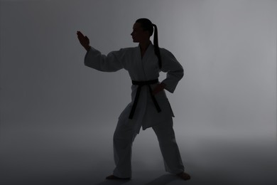 Photo of Silhouette of woman in kimono practicing karate on light background