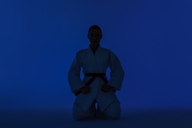 Photo of Silhouette of karate fighter in kimono on dark blue background