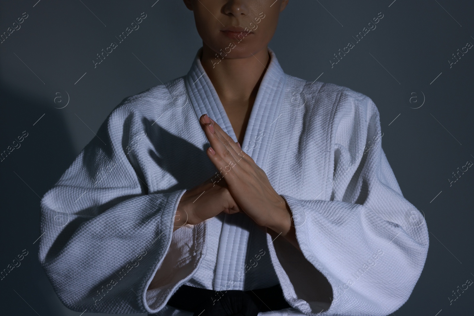 Photo of Karate fighter in kimono on grey background, closeup