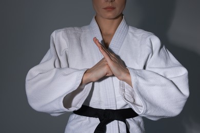 Photo of Karate fighter in kimono on grey background, closeup