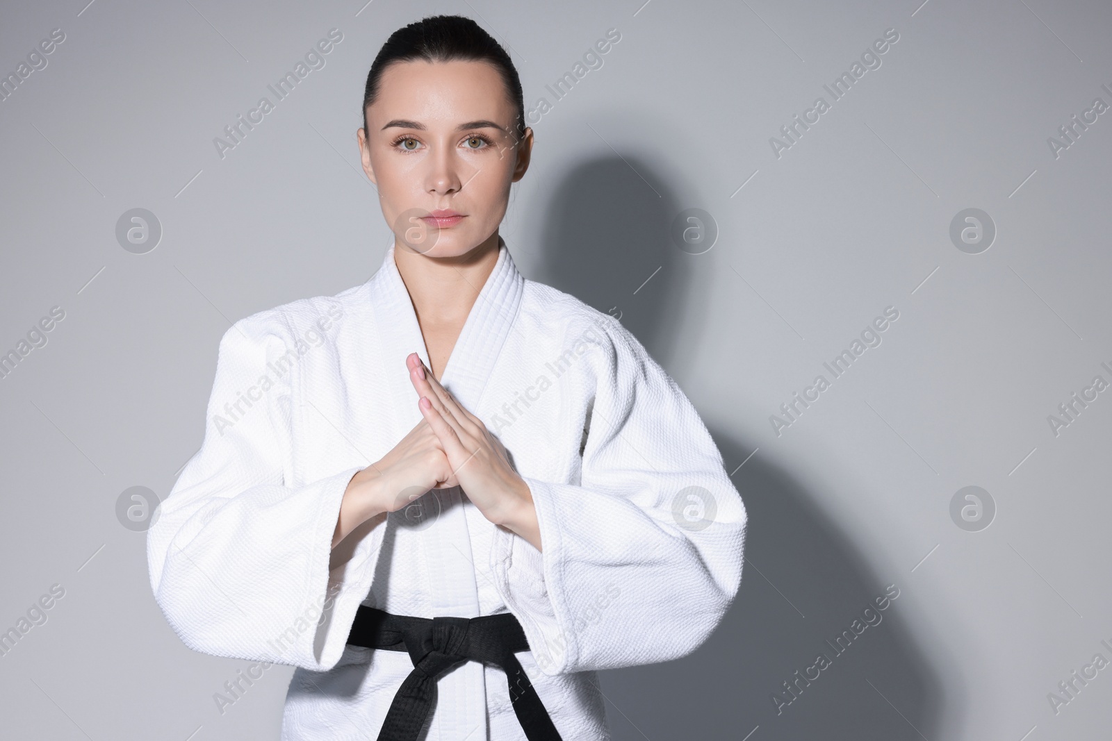 Photo of Karate fighter in kimono on grey background, space for text