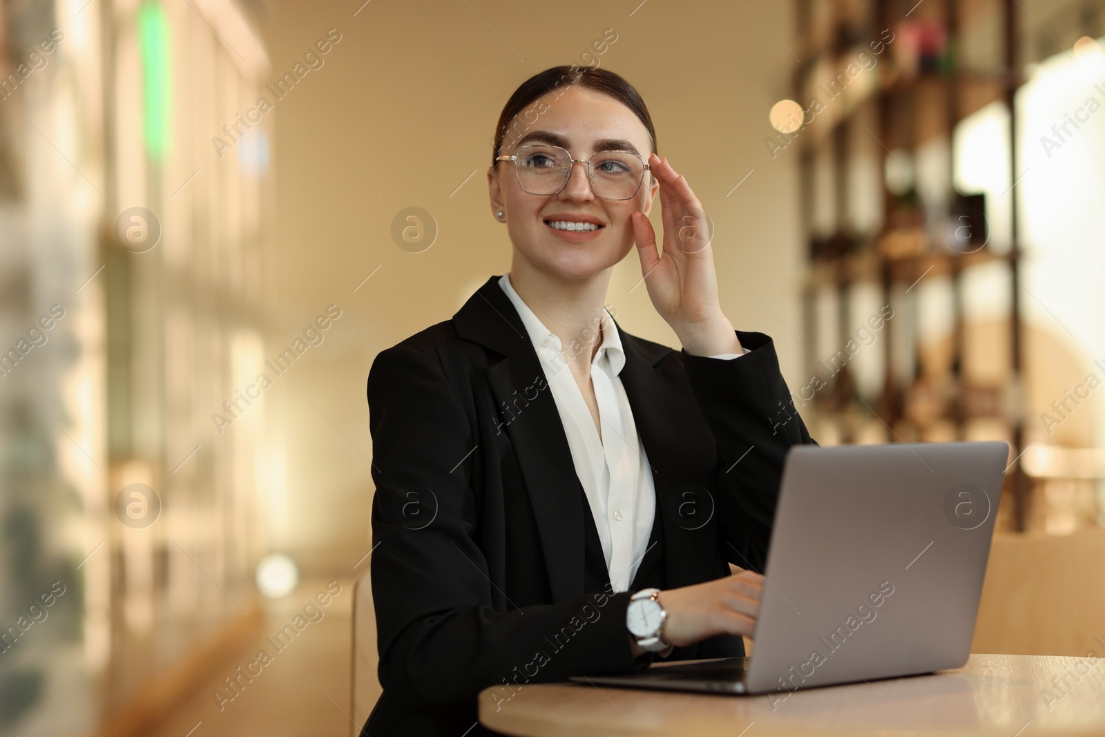 Photo of Woman in stylish formal suit working on laptop at table indoors