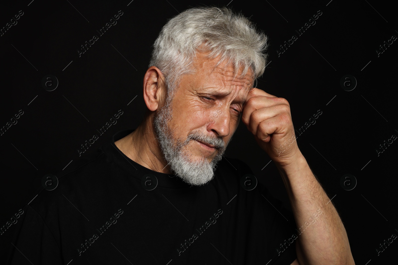 Photo of Sad senior man crying on black background