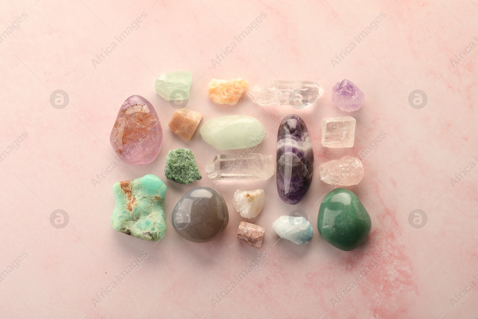 Photo of Beautiful natural gemstones on light pink background, flat lay